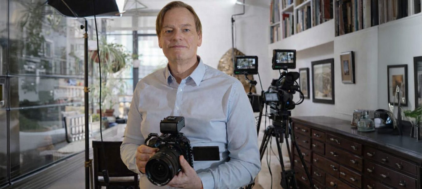 Homme tenant un appareil photo dans un studio avec des caméras en arrière-plan.