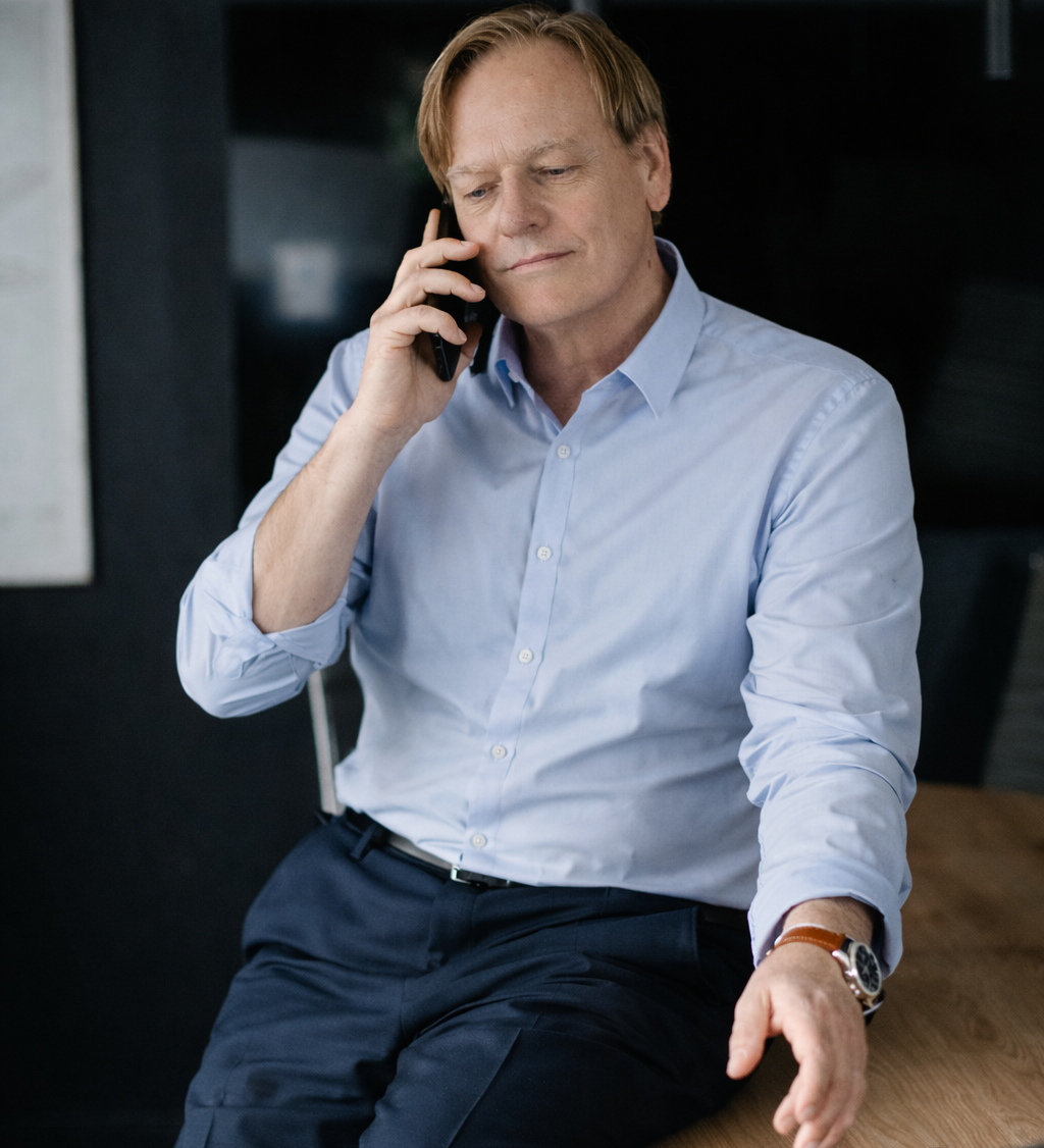 Un premier échange stratégique, et sans aucun engagement avec Olivier Dupont Homme en chemise claire, parlant au téléphone, assis sur une table en bois.