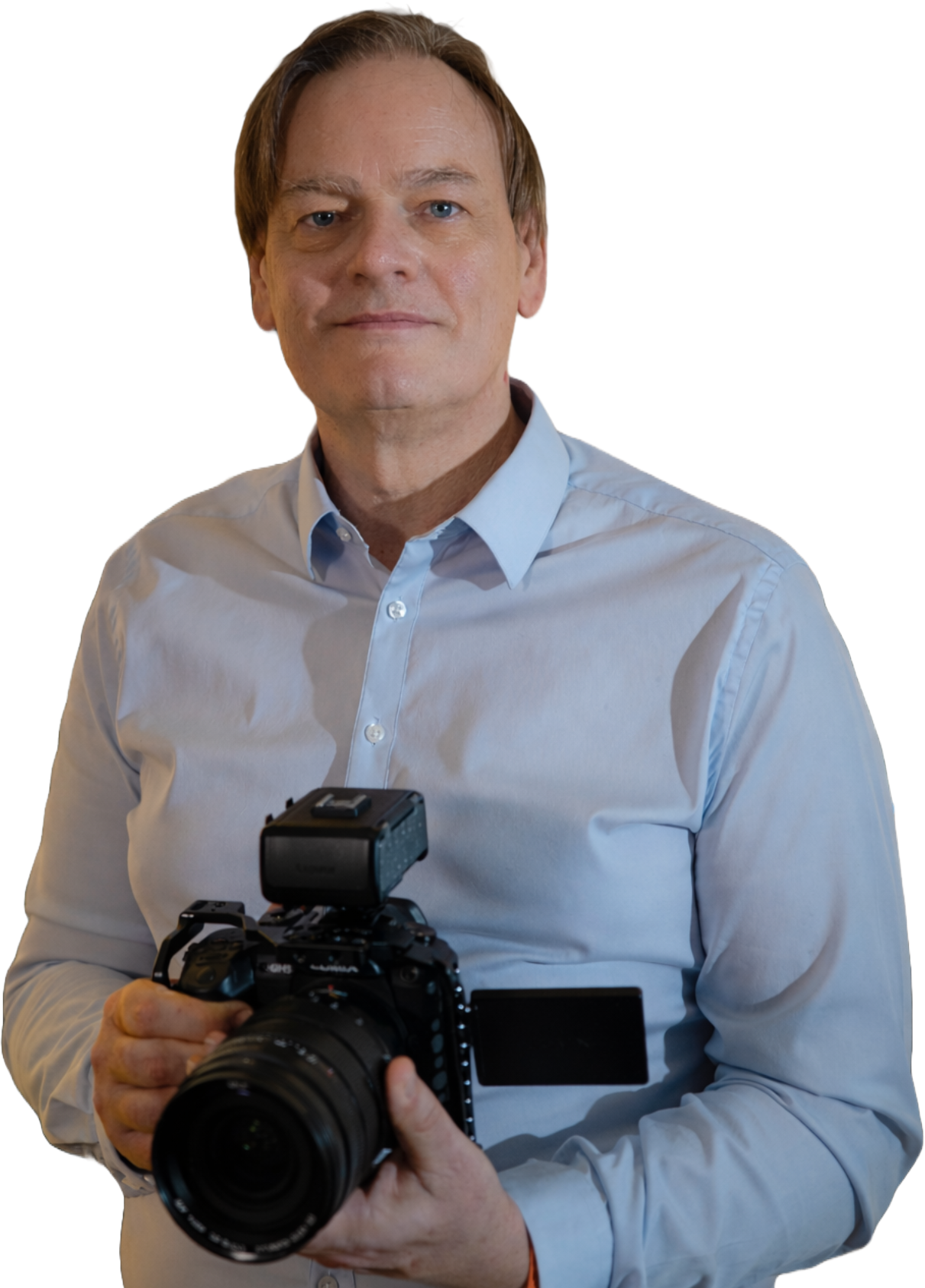 Homme tenant un appareil photo, vêtu d'une chemise claire.